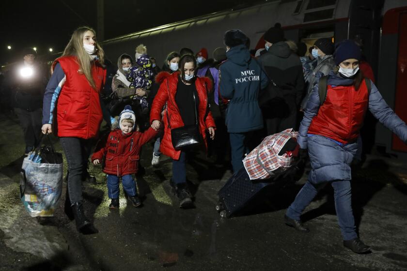 People from the Donetsk and Luhansk regions, the territory controlled by a pro-Russia separatist governments in eastern Ukraine, walk from a train to be taken to temporary residences in the Volgograd region, at the railway station in Volzhsky, Volgograd region, Russia, on Sunday, Feb. 20, 2022. Ukrainian President Volodymyr Zelenskyy, facing a sharp spike in violence in and around territory held by Russia-backed rebels and increasingly dire warnings that Russia plans to invade, has called for Russian President Vladimir Putin to meet him and seek a resolution to the crisis. (AP Photo/Alexandr Kulikov)