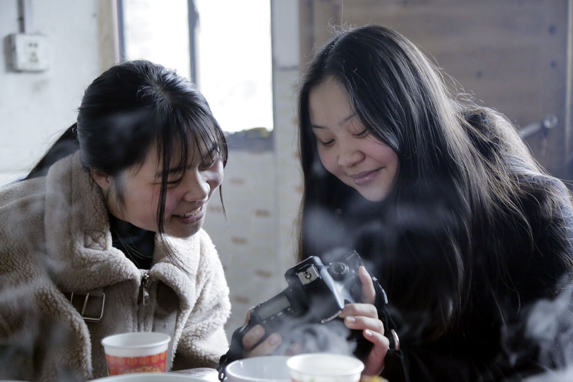 Esther Frederick shows her identical twin, Zeng Shuangjie, photos she took with her camera. Esther is interested in photography, art, baking and fashion, while Shuangjie likes badminton, pingpong, music and writing Chinese characters. The girls were separated when they were toddlers.