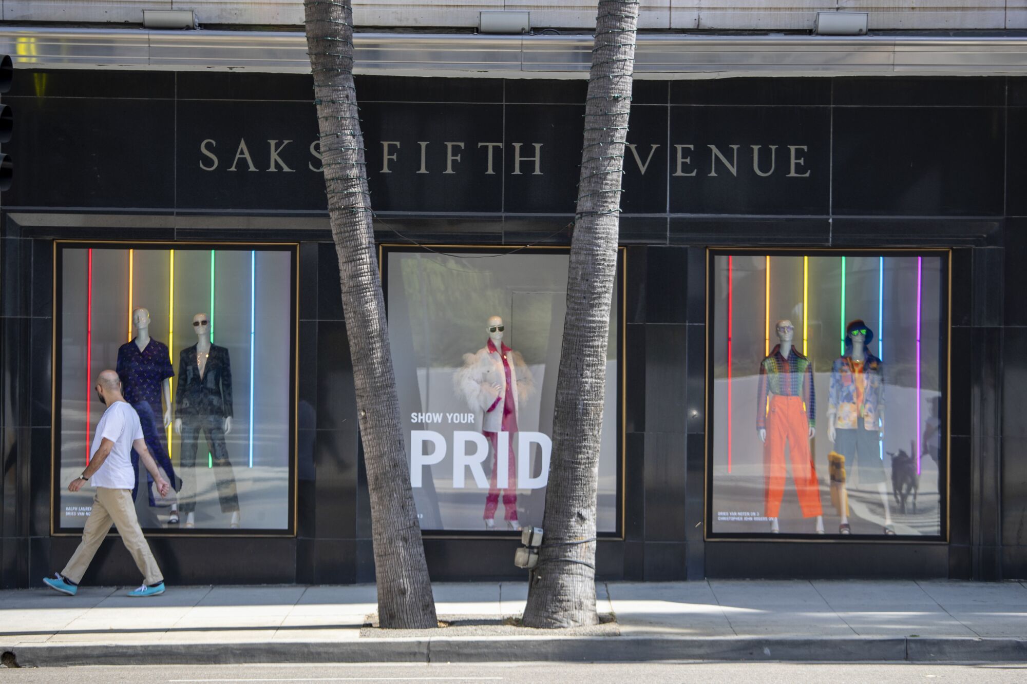 A man walks past a window at Saks Fifth Avenue in Beverly Hills.