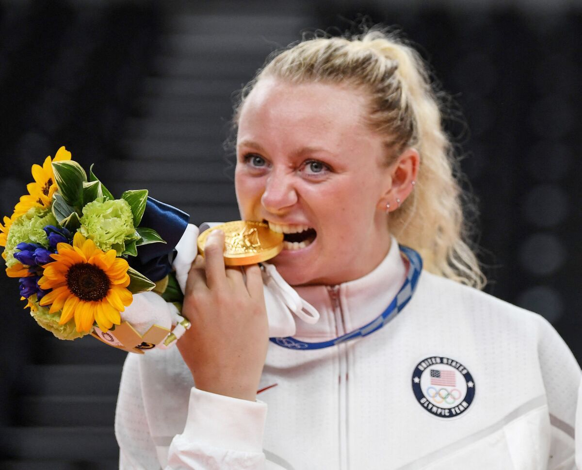 Volleyball player Jordyn Poulter bites her Olympic gold medal in 2021. 