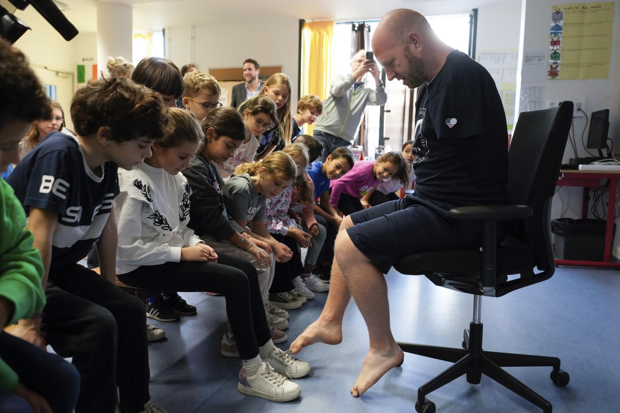 Matt Stutzman visits a Paris school and ties a student's shoe with his toes. 