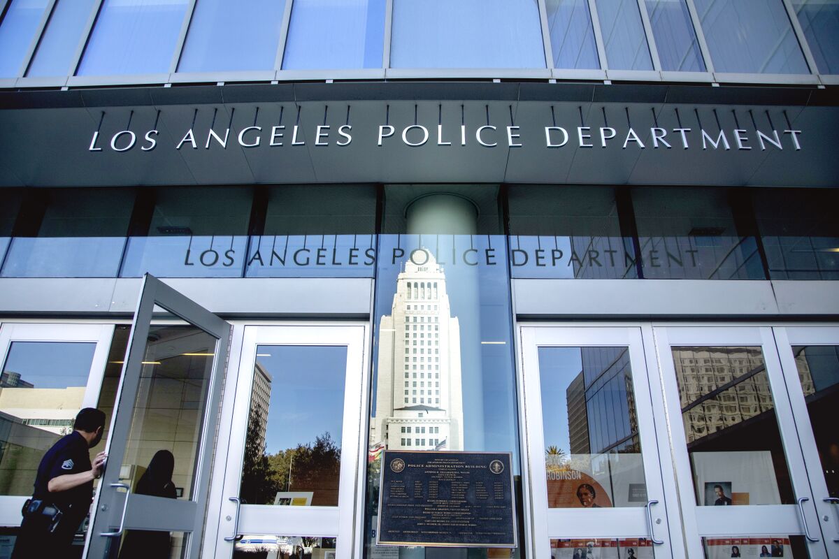A view of the exterior of Los Angeles Police Department Headquarters. A police officer enters the main entry doors. 
