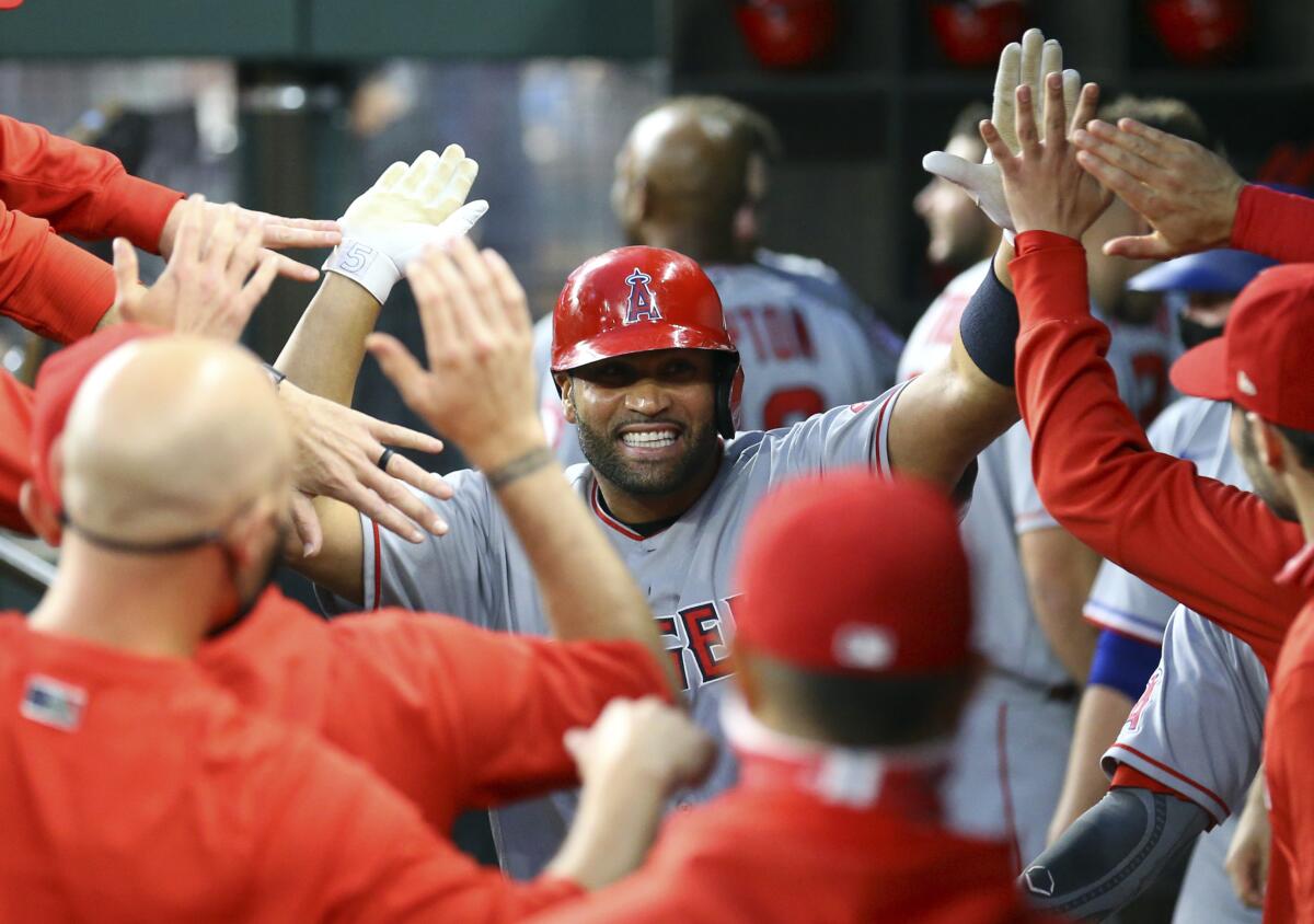 Albert Pujols smiles and exchanges high fives as he is greeted in the dugout after hitting a home run.