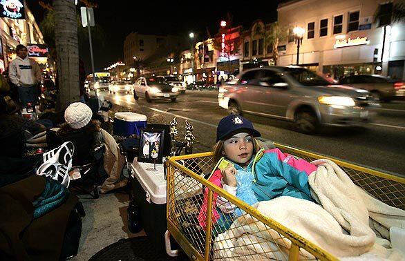 Bailey Campbell, 10, of Downey rests in comfort in a wagon as she and her father prepare to spend the night along Colorado Boulevard in a prime spot to watch the Rose Parade. This is the third year that she and her dad have camped out in Pasadena for the parade.