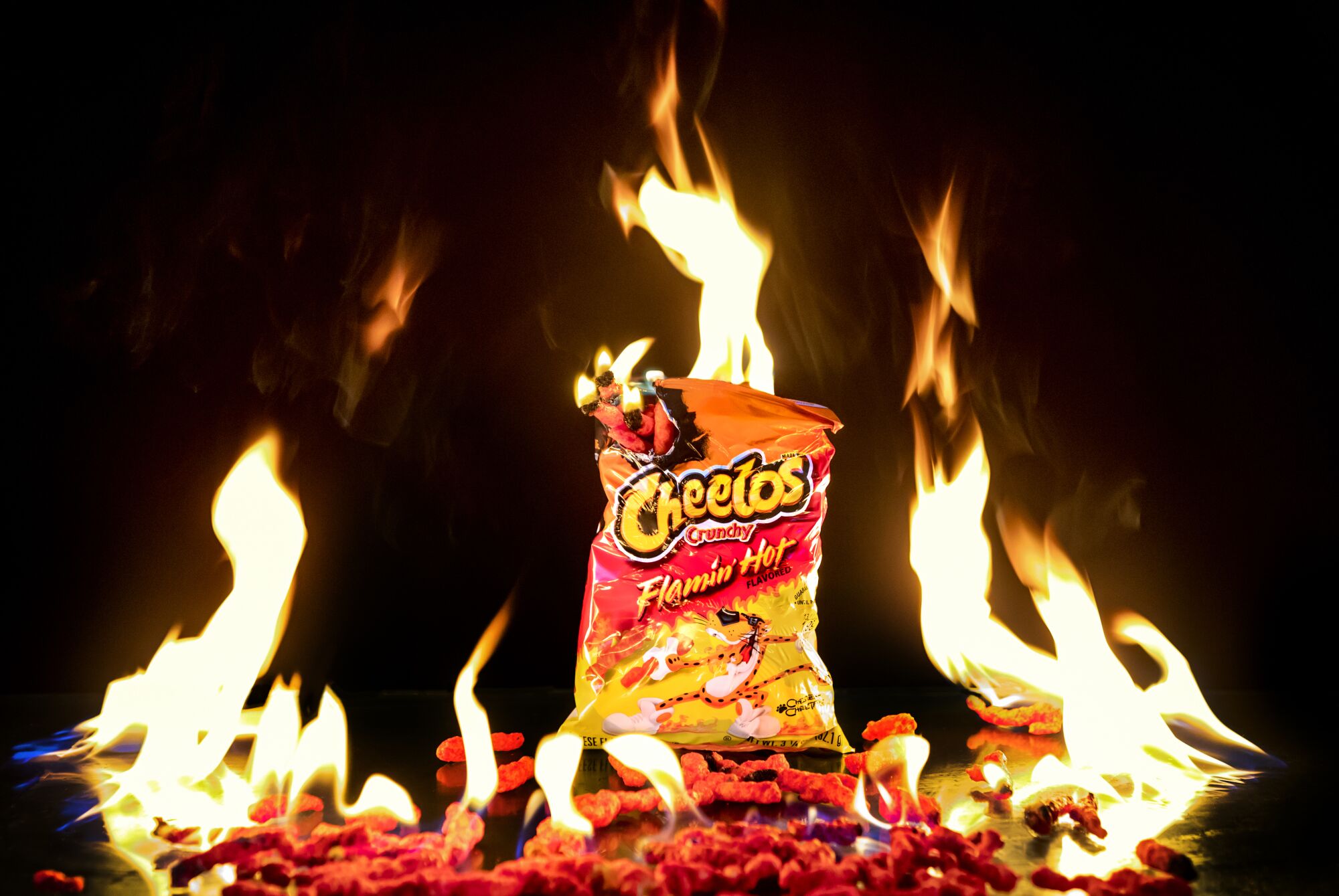  A bag of Cheetos is surrounded  by fire. 
