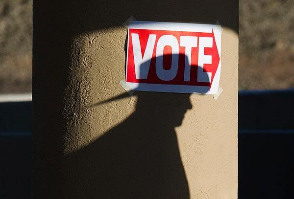 A shadow of a man wearing a cowboy hat falls on a pillar as he enters the polling place at Wickenburg Community Center in Wickenburg, Ariz. Republican voters cast ballots in primaries in Arizona and Michigan. The latest polls show that Mitt Romney has opened up a double-digit lead in Arizona, where a significant percentage of the population shares his Mormon faith and where he probably benefited from large numbers of early voters.