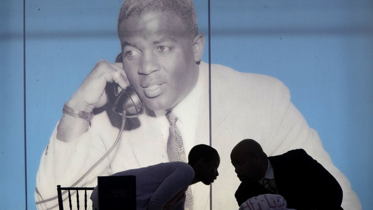 Jackie Robinson Museum employees are framed by a giant poster of legendary baseball player at a groundbreaking ceremony Thursday.