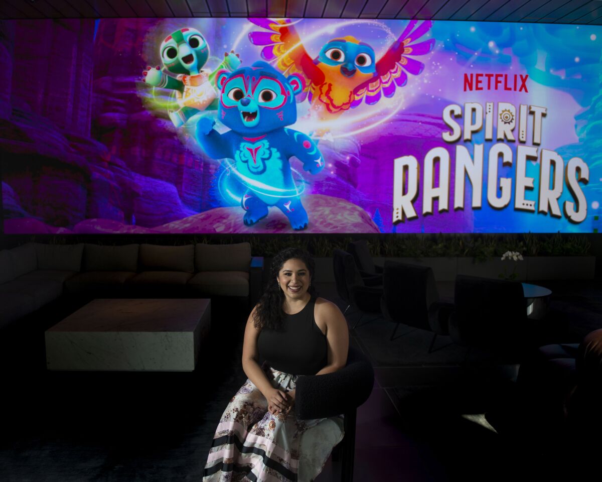 A woman sits in a room in front of a screen that says Netflix Spirit Rangers with colorful art