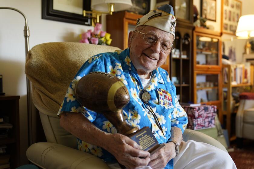 Mickey Ganitch, a 101-year-old survivor of the attack on Pearl Harbor, holds a football statue he was given, in the living room of his home in San Leandro, Calif., Nov. 20, 2020. Ganitch was getting ready for a match pitting his ship, the USS Pennsylvania, against the USS Arizona when Japanese planes bombed Pearl Harbor on Dec. 7, 1941. The game never happened. Instead, Ganitch spent the morning, still in his football uniform, looking out for attacking planes that anti-aircraft gunners could shoot down. (AP Photo/Eric Risberg)