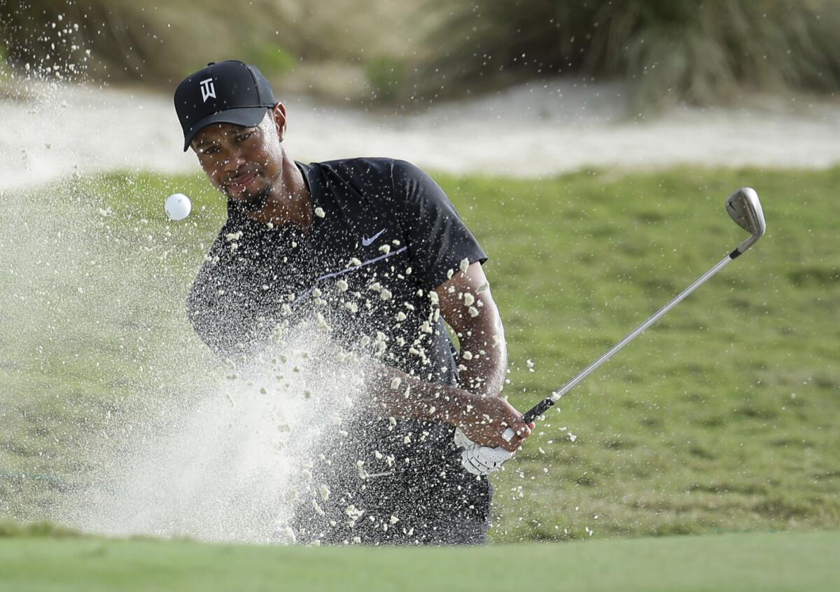Tiger Woods hits from a bunker onto the 14th green Thursday in Nassau, Bahamas.
