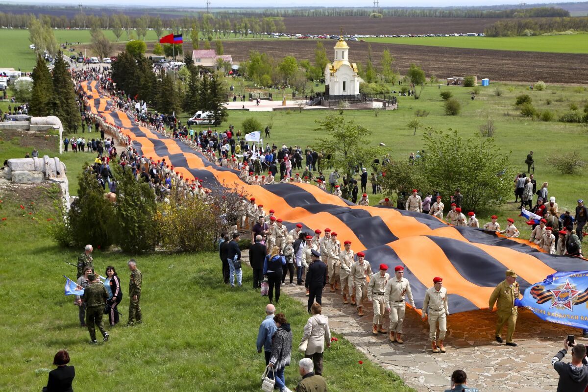 Activists carry a 300 meter long St. George ribbon, which has become a symbol of the pro-Russian insurgency in eastern Ukraine, during celebrations of the Victory Day at a World War II memorial in Saur-Mogila, about 60 km. (31 miles) east of Donetsk, eastern Ukraine, Saturday, May 8, 2021. Efforts have stalled to end the conflict between Russia-backed rebels and Ukrainian forces, which has killed more than 14,000 people since it broke out in 2014. Russia, which claims it has no military presence in eastern Ukraine, fueled the tensions this year by massing troops and conducting large-scale military exercises near its border with Ukraine. (AP Photo/Alexei Alexandrov)