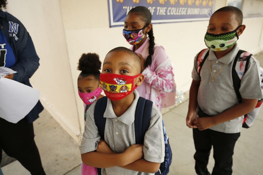 HARBOR CITY, CA - AUGUST 16: Second grade student Aedan Davis, from with siblings TK student Alayna, TK, left, Aaliyah, 4th grade and Ahmier, 5th grade, left to right, make their way to the front door of Normont Elementary School on the first day of in class instruction on August 16, as LAUSD officials welcome students, teachers, principals, at various school sites across Los Angeles. For the younger students it will be their first time in a classroom. Normont Elementary on Monday, Aug. 16, 2021 in Harbor City, CA. (Al Seib / Los Angeles Times).