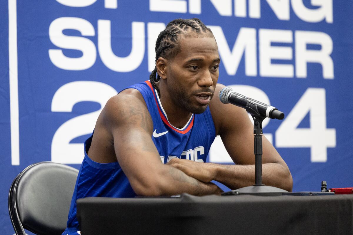 Kawhi Leonard speaks into a microphone on a table as he fields questions at Clippers media day.