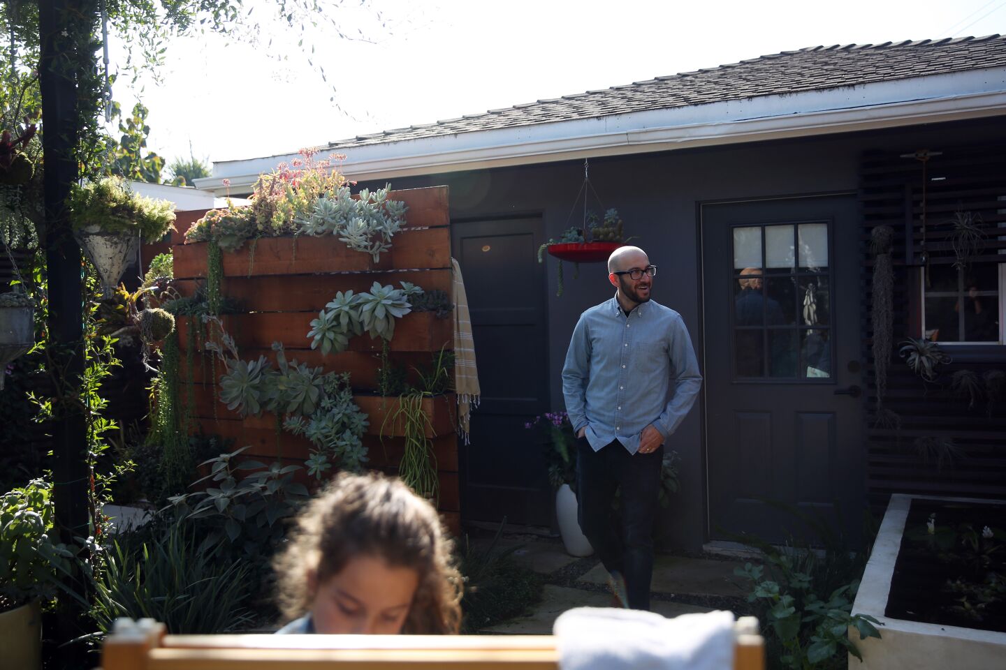 Nili Glatstein, 7, colors on an easel with her dad, Jeremy Glatstein, right, in the backyard. Garden designer Dustin Gimbel created a custom planter, left, for Jeremy's plant collections.