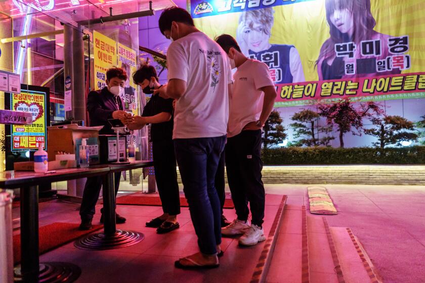 DAEJEON, SOUTH KOREA -- FRIDAY, JUNE 5, 2020: Bouncers ask patrons for their QR codes before allowing them into Nightclub 7 in Daejeon, South Korea, on June 5, 2020. The South Korean government is rolling out the use of QR codes before entry, as a precaution to allow for contact tracing, in an event of a coronavirus outbreak. The QR code is required in certain types of establishments: night clubs, karaokes, indoor sports facilities and concert spaces. (Marcus Yam / Los Angeles Times)