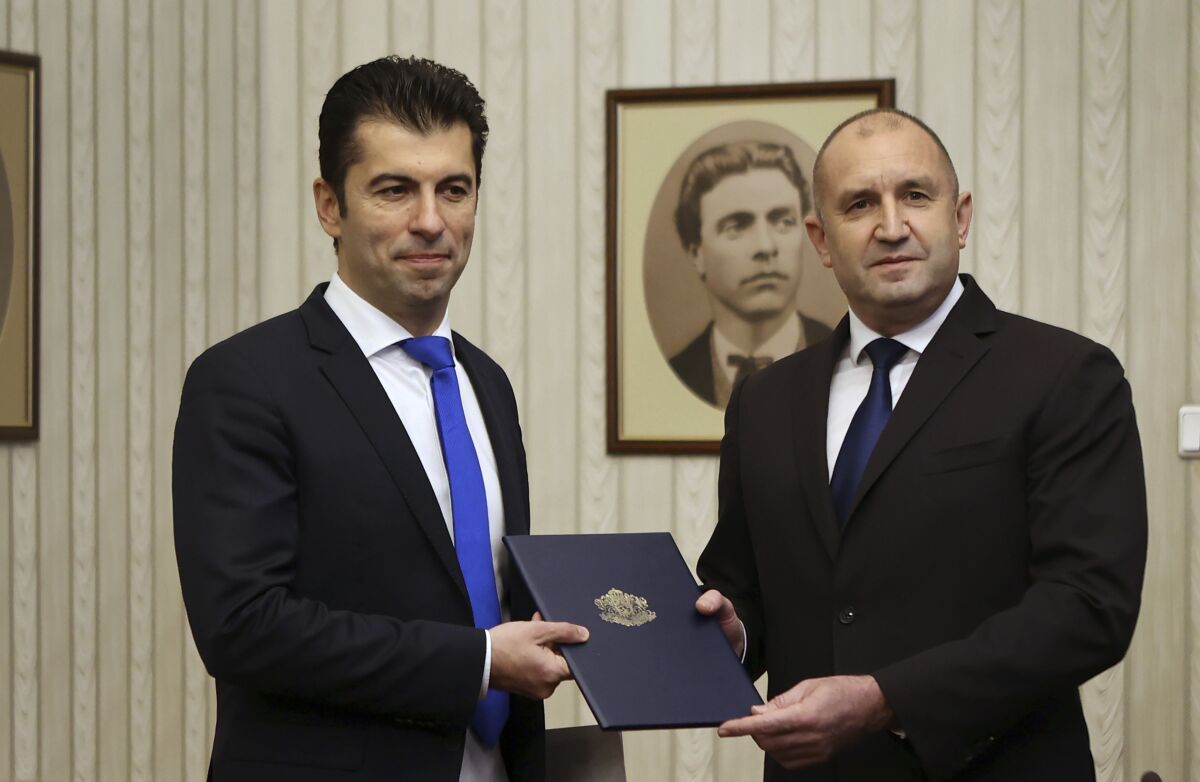 FILE - Kiril Petkov, left, co-leader of the We Continue the Change party, receives a mandate to form a new government from Bulgarian President Rumen Radev, Sofia, Dec. 11, 2021. Bulgaria’s top leaders are under self-imposed quarantine after being in contact with the speaker of parliament who tested positive for coronavirus, the country’s chief health inspector said on Tuesday, Jan. 11, 2022. Speaker Nikola Minchev felt unwell and took a test that turned out positive for COVID-19 after emerging from a six-hour meeting of the country’s consultative National Security Council on Monday, chaired by President Rumen Radev and attended by Prime Minister Kiril Petkov, several key ministers and heads of security and intelligence services, as well as leaders of the parties represented in parliament. (AP Photo/Valentina Petrova, file)