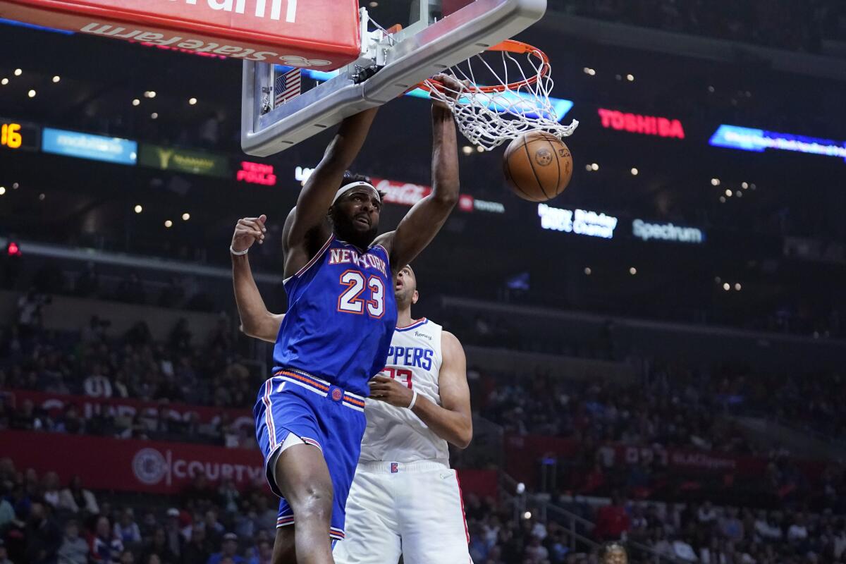 New York Knicks center Mitchell Robinson dunks in front of Clippers forward Nicolas Batum.