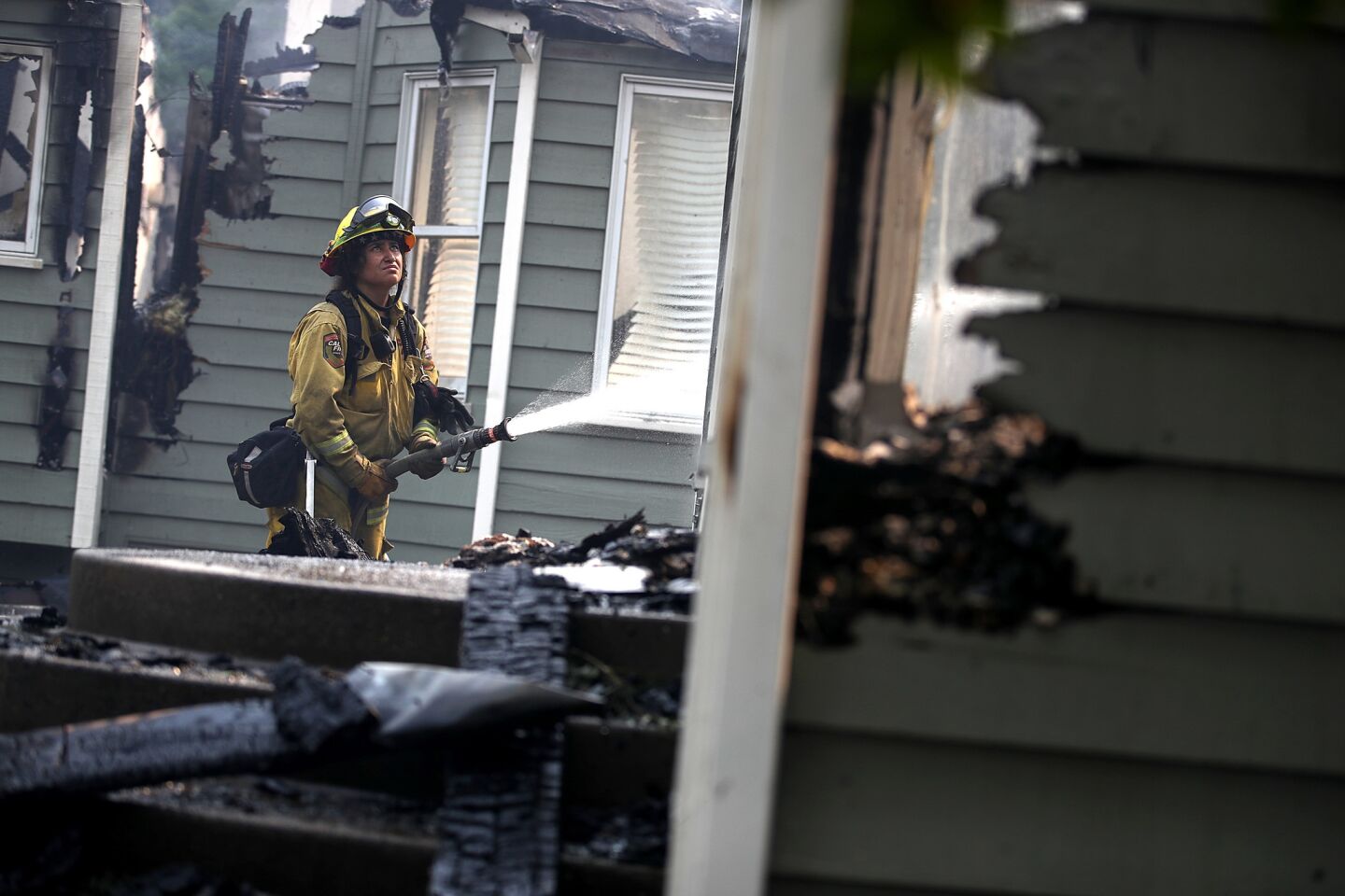 A firefighter sprays water on what's left of a Redding home damaged by the Carr fire on July 27.