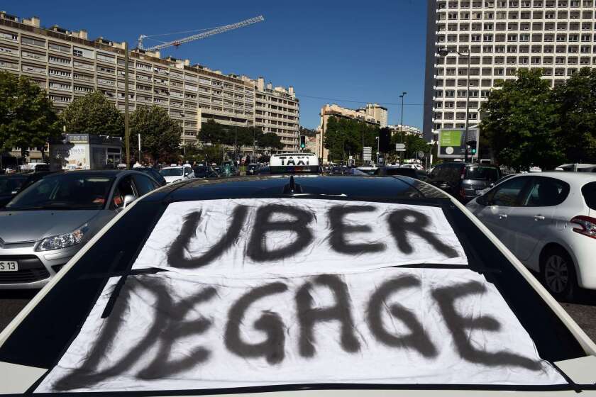 A banner that translates as "Uber get out" is displayed across a taxi windshield during a June 25 protest in Marseille, France, as taxi drivers demonstrated against UberPop, a popular taxi app that is facing fierce opposition from traditional cabs.