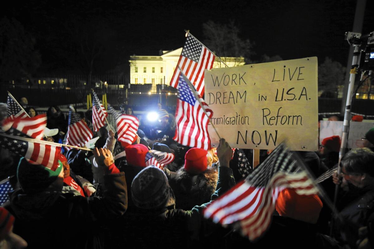 Rally participants wave American flags and signs as they gather in front of the White House in Washington on Thursday as President Obama prepares to address the nation on immigration reform.