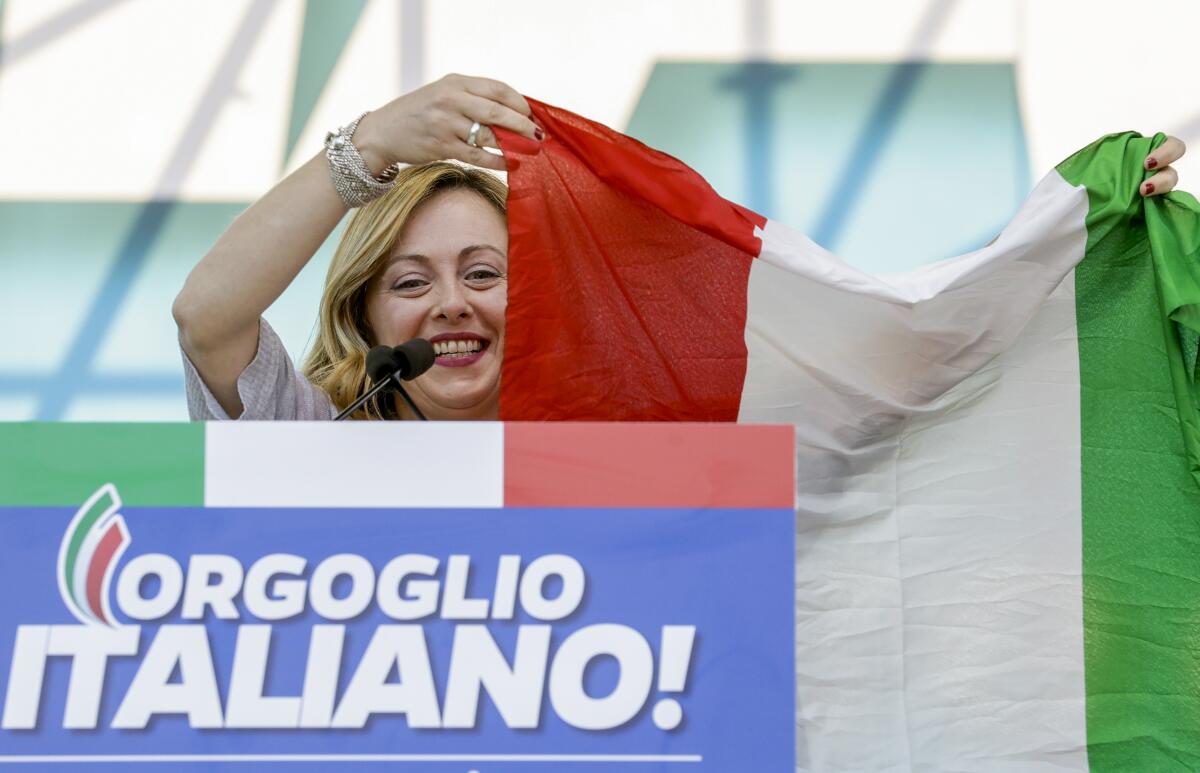 FILE — Giorgia Meloni holds an Italian flag as she addresses a rally in Rome, Saturday, Oct. 19, 2019. With God, homeland and "natural" family prominent in her political manifesto, Giorgia Meloni, whose Fratelli d'Italia (Brothers of Italy) party with neo-fascist roots has been fast rising in popularity in view of the upcoming Sept. 25 elections for Parliament, is positioning herself to become Italy's first far-right premier and the first woman to hold that office. (AP Photo/Andrew Medichini)
