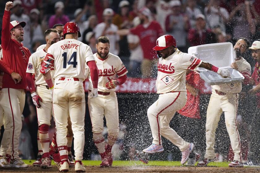 Willie Calhoun celebrates with teammates at home plate after hitting a home run against the Mariners at Angel Stadium.