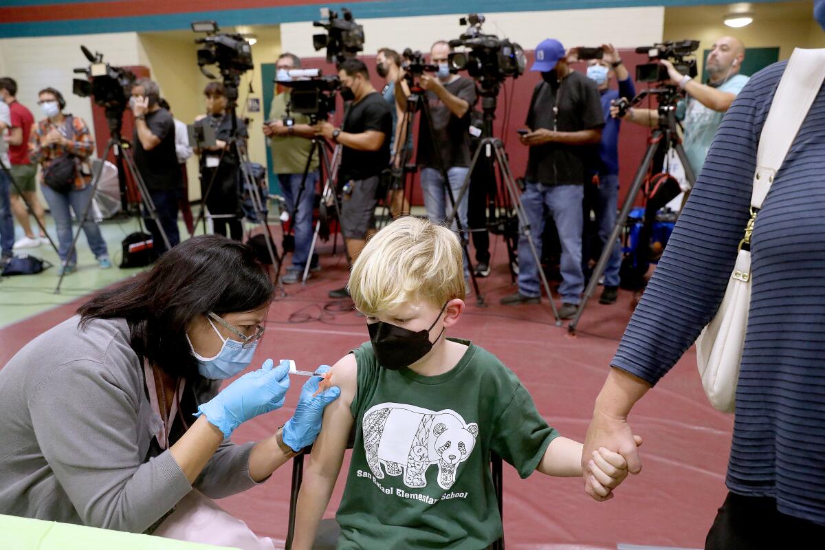 A boy receives a shot on his shoulder.