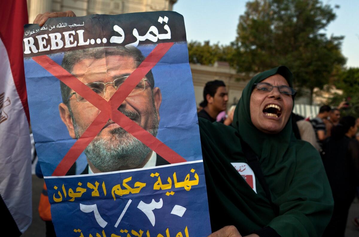 A women holds up a defaced poster of Egyptian President Mohamed Morsi outside the presidential palace in Cairo.