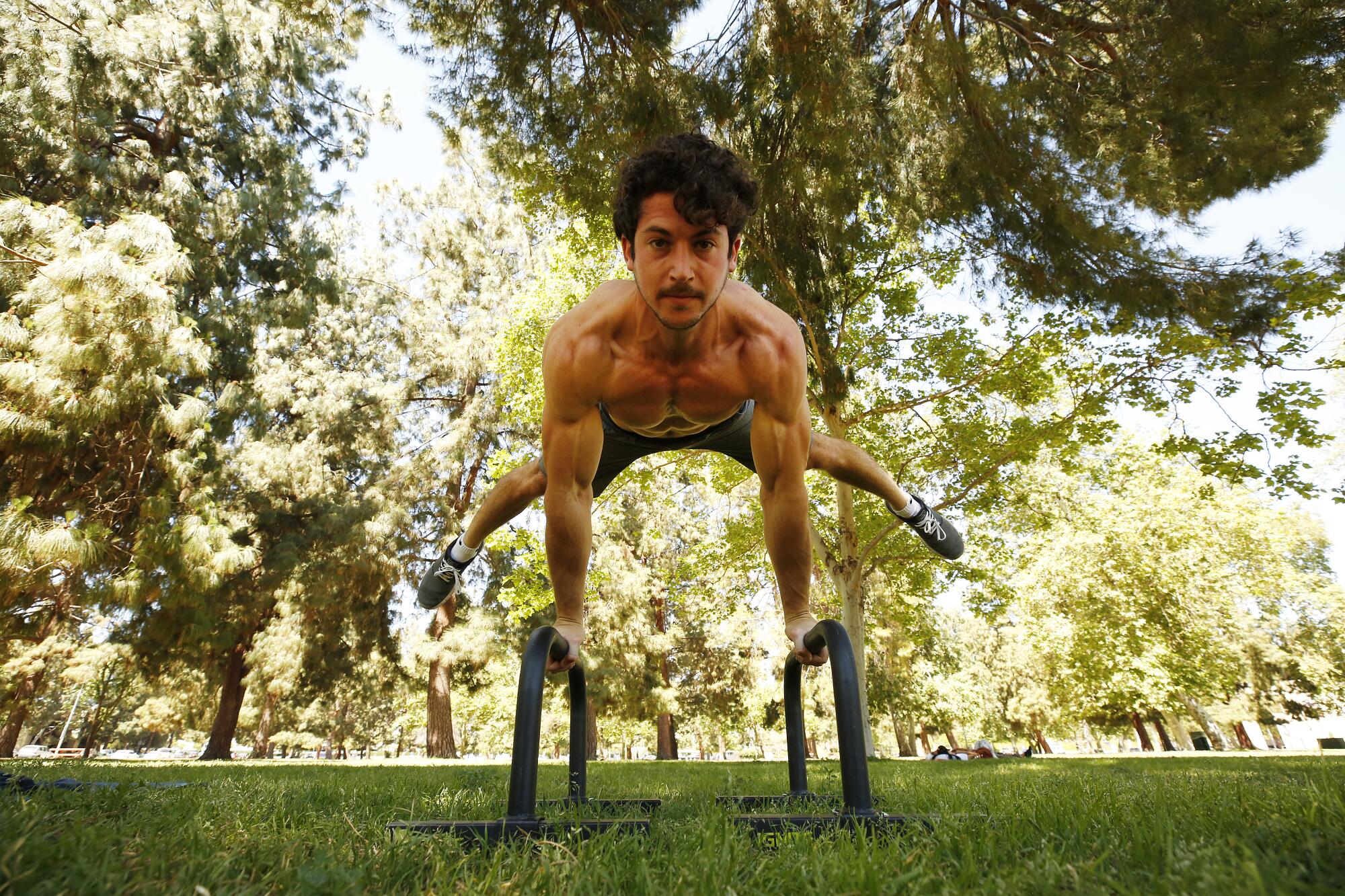 Personal trainer Yonatan Mishan works out in the shade at Warner Center Park in Woodland Hills.