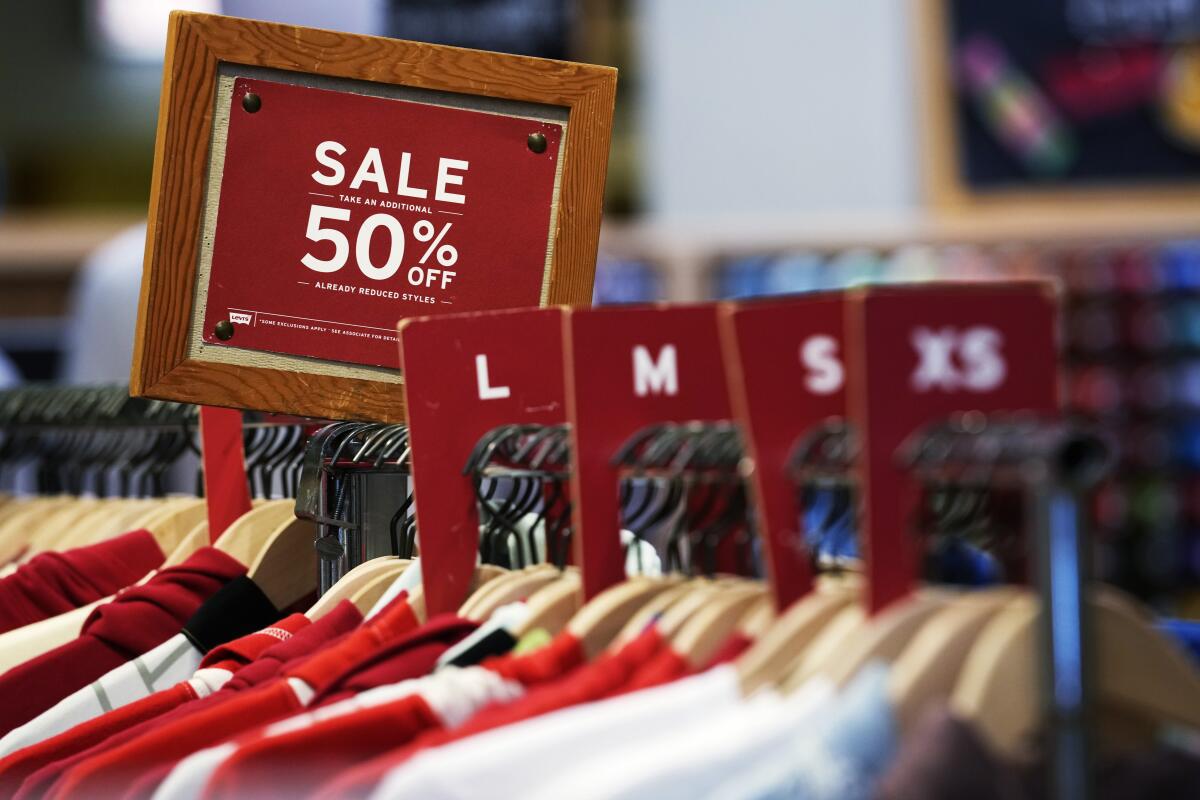 A sale sign is displayed on a rack of clothes at a store