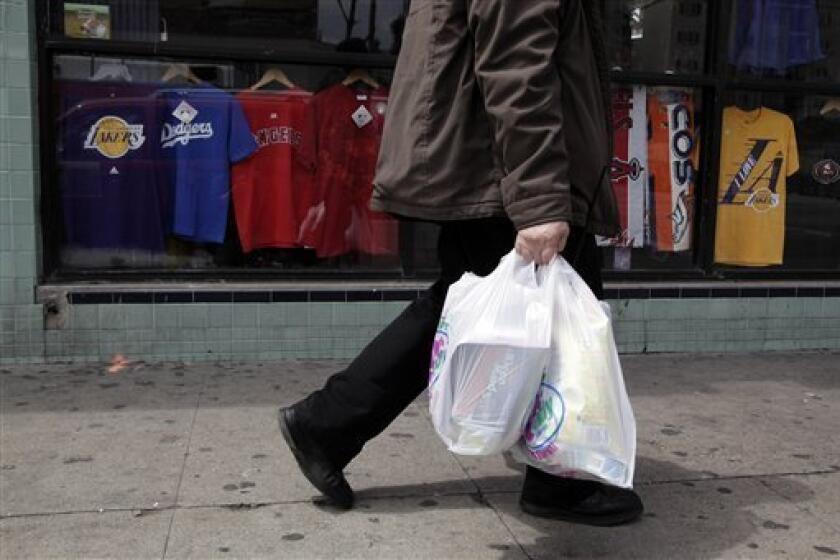File photo: A man walks along the street with plastic bags in Los Angeles, Thursday, May 24, 2012. Now that the city of Los Angeles has taken the first step toward banning plastic bags, it appears the little utilitarian bags themselves may be headed for the trash heap of history. (AP Photo/Jae C. Hong)
