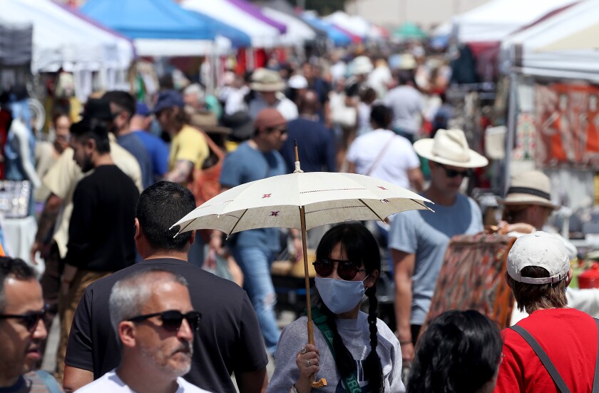 A person wears a mask at a crowded outdoor market.