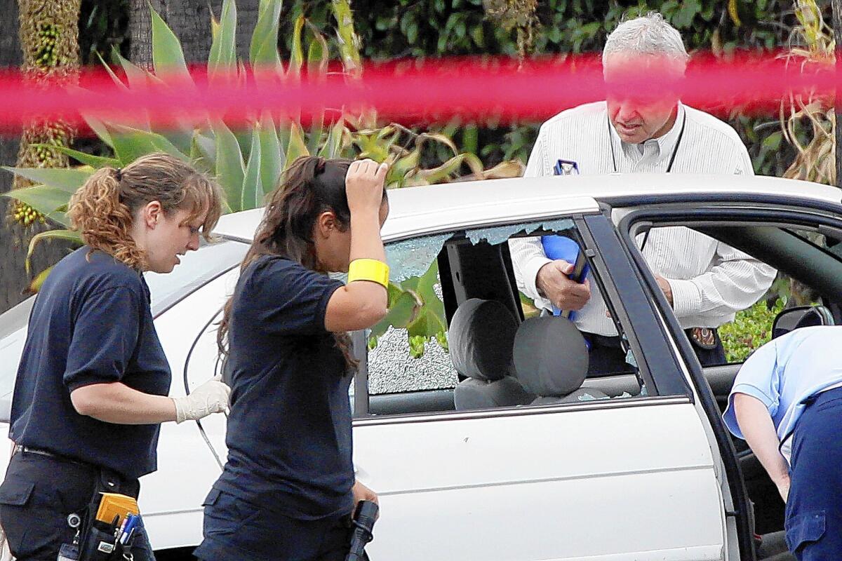 Investigators look last June at the car two LAPD officers were in when a man reportedly shot at them. The only bullets and spent shell casings recovered were those belonging to the officers.