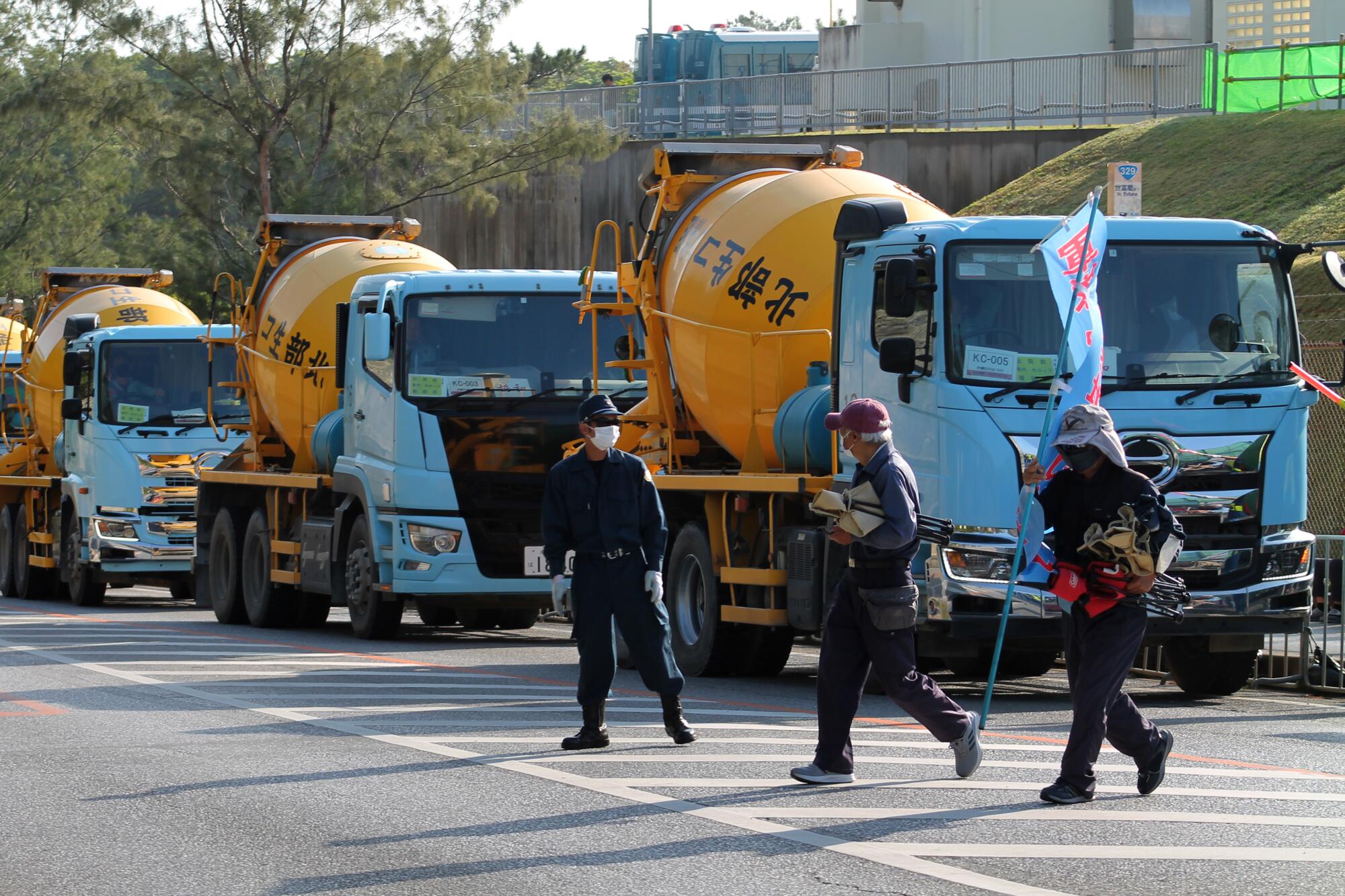 日本冲绳岛上的水泥车排成一排，抗议活动封锁了他们的道路。