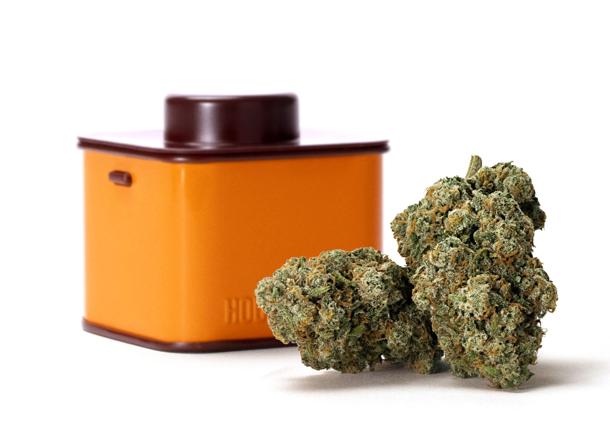 An orange tin next to a cannabis nugget.