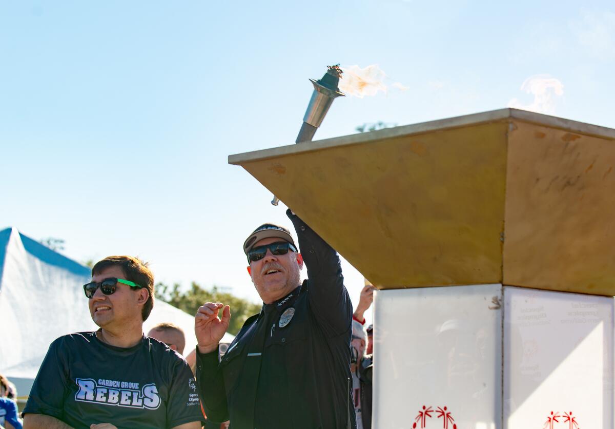 Garrett Thompson, left, and Police Chief Matt Sheppard light the torch of the 2023 Special Olympics SoCal Fall Games.