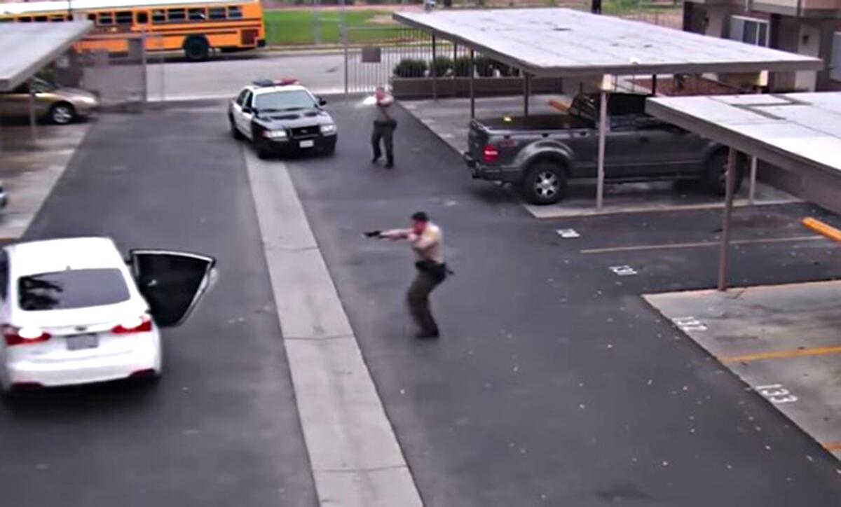 Video still showing sheriff's deputies in a parking lot shooting at a car with one door open