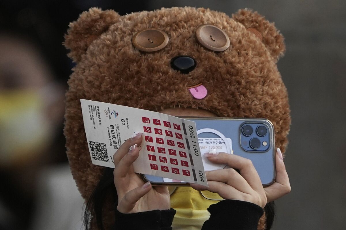 A person in a bear hat holds up a piece of paper and a phone.