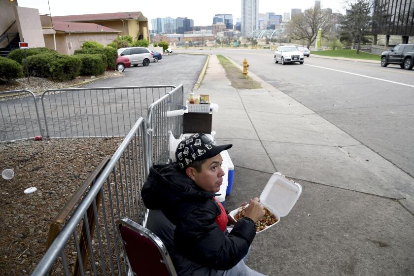 Lincoln Montero eats outside a motel designated for migrants after helping his aunt Yesenia sell home-cooked Venezuelan-style food to fellow Venezuelan migrants sheltering here in Denver, Colorado, Thursday, April 18, 2024. Montero said he traveled to Denver the week before, to unite with his aunt who has been here four months. (AP Photo/Thomas Peipert)