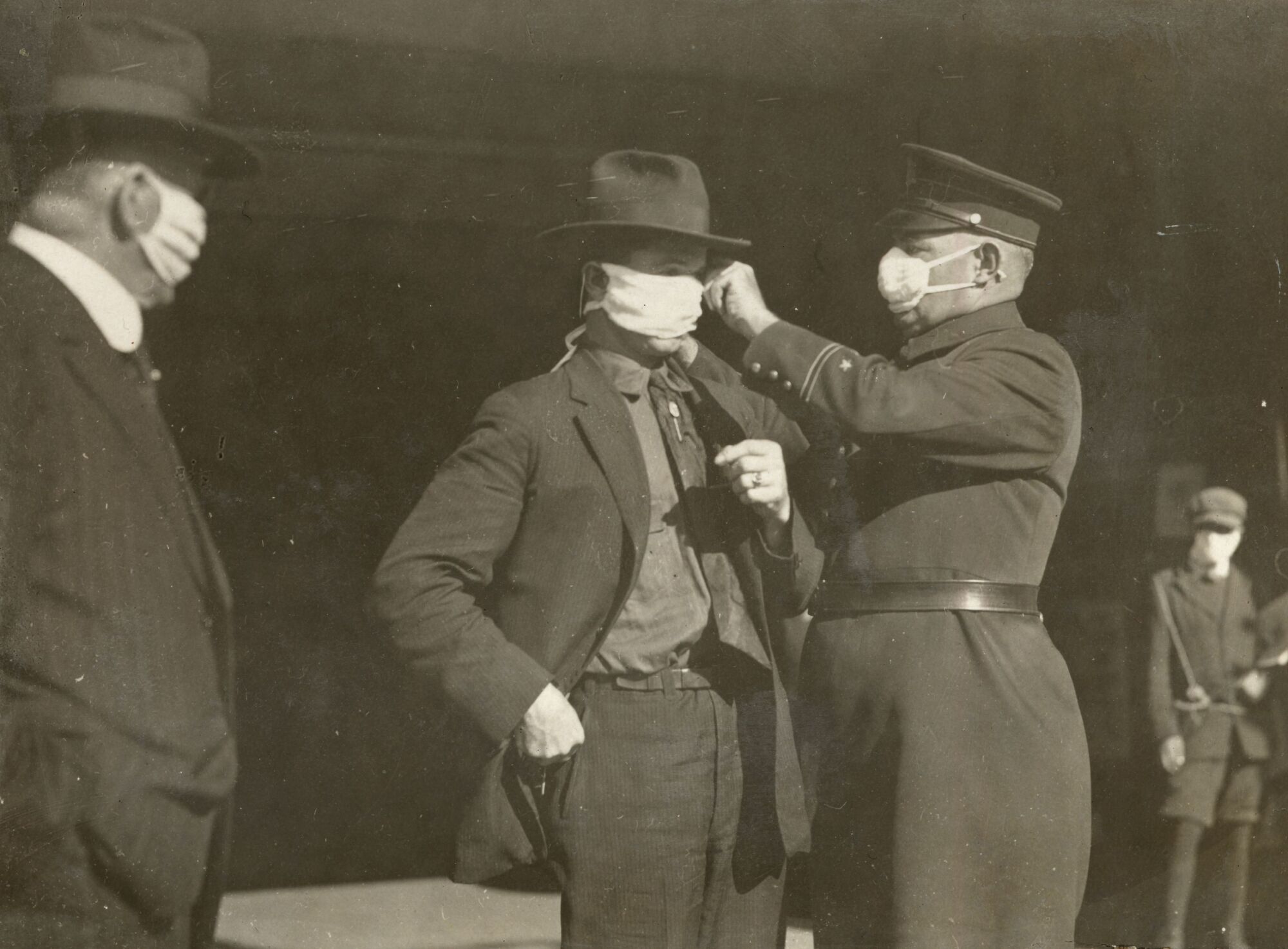  A police officer adjusts a man's flu mask in San Francisco during the 1918 pandemic. 