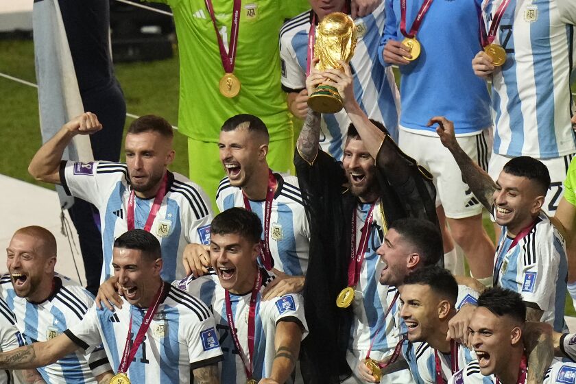 Argentina's Lionel Messi holds the winners trophy as he celebrates with teammates after their win in the World Cup final soccer match against France at the Lusail Stadium in Lusail, Qatar, Sunday, Dec. 18, 2022. (AP Photo/Francisco Seco)