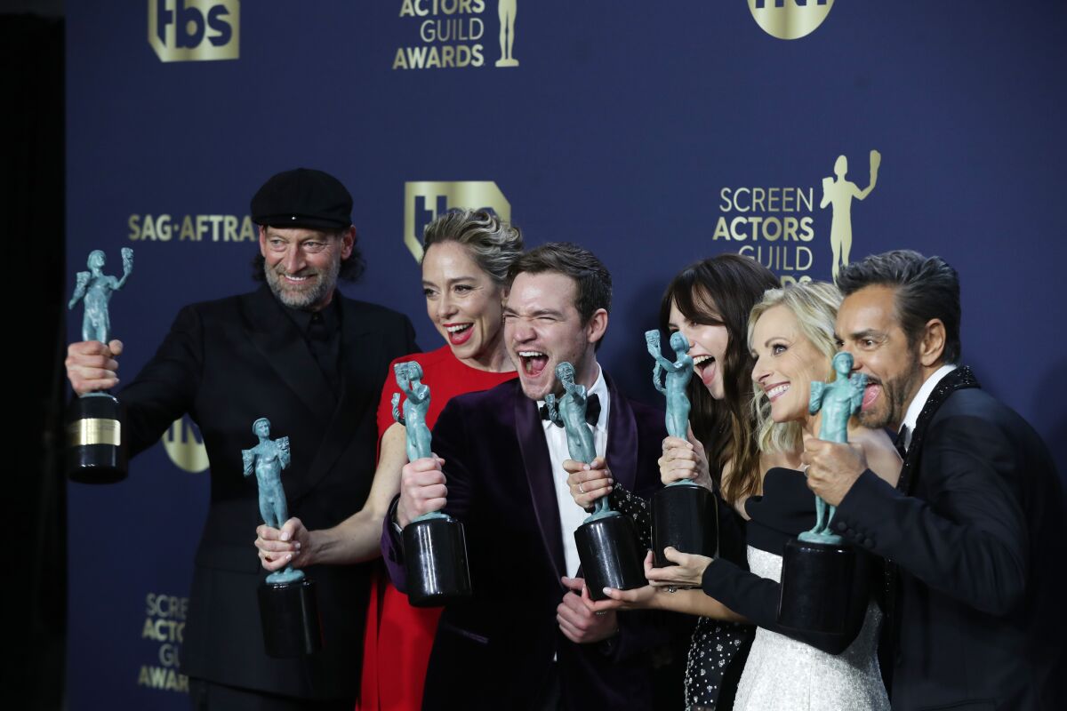 A line of men and women holding up SAG award statuettes.