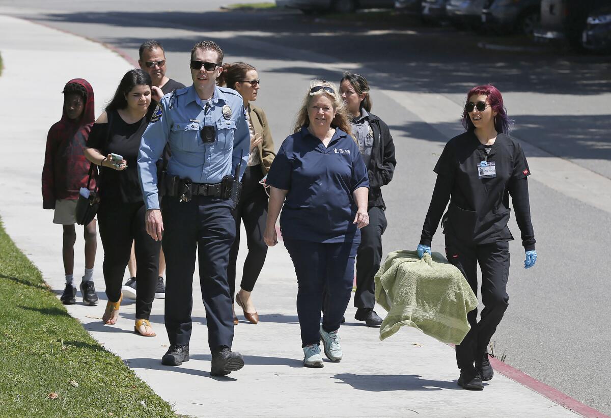 Officer Nick Ott, Debbie McGuire and Michele Saldana carry a duck in a carrier.