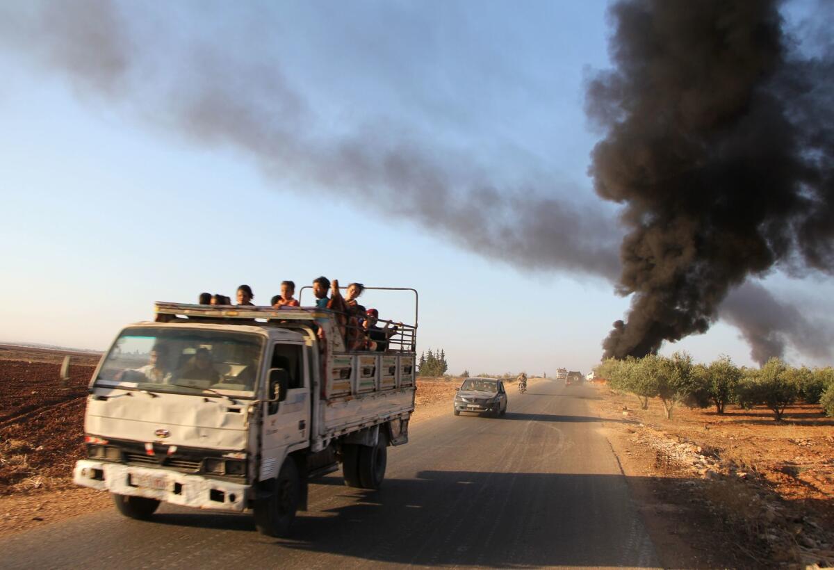 Syrians fleeing from the town of Suran, in northern Hama province, drive past burning vehicles on Thursday after fighters from the Jund al Aqsa insurgent group took control of the town from Syrian government forces.