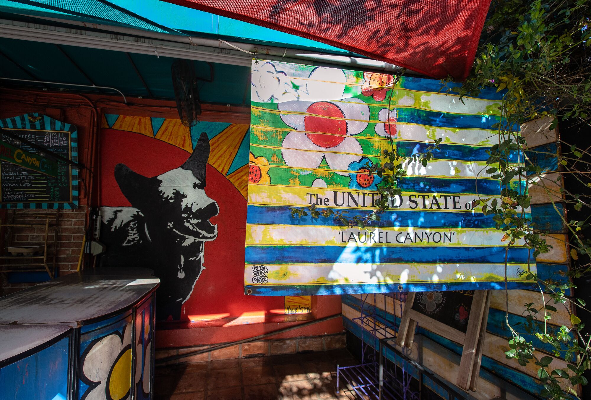 A colorful flag with a flower and the words "The United State of Laurel Canyon" hangs outside a store.