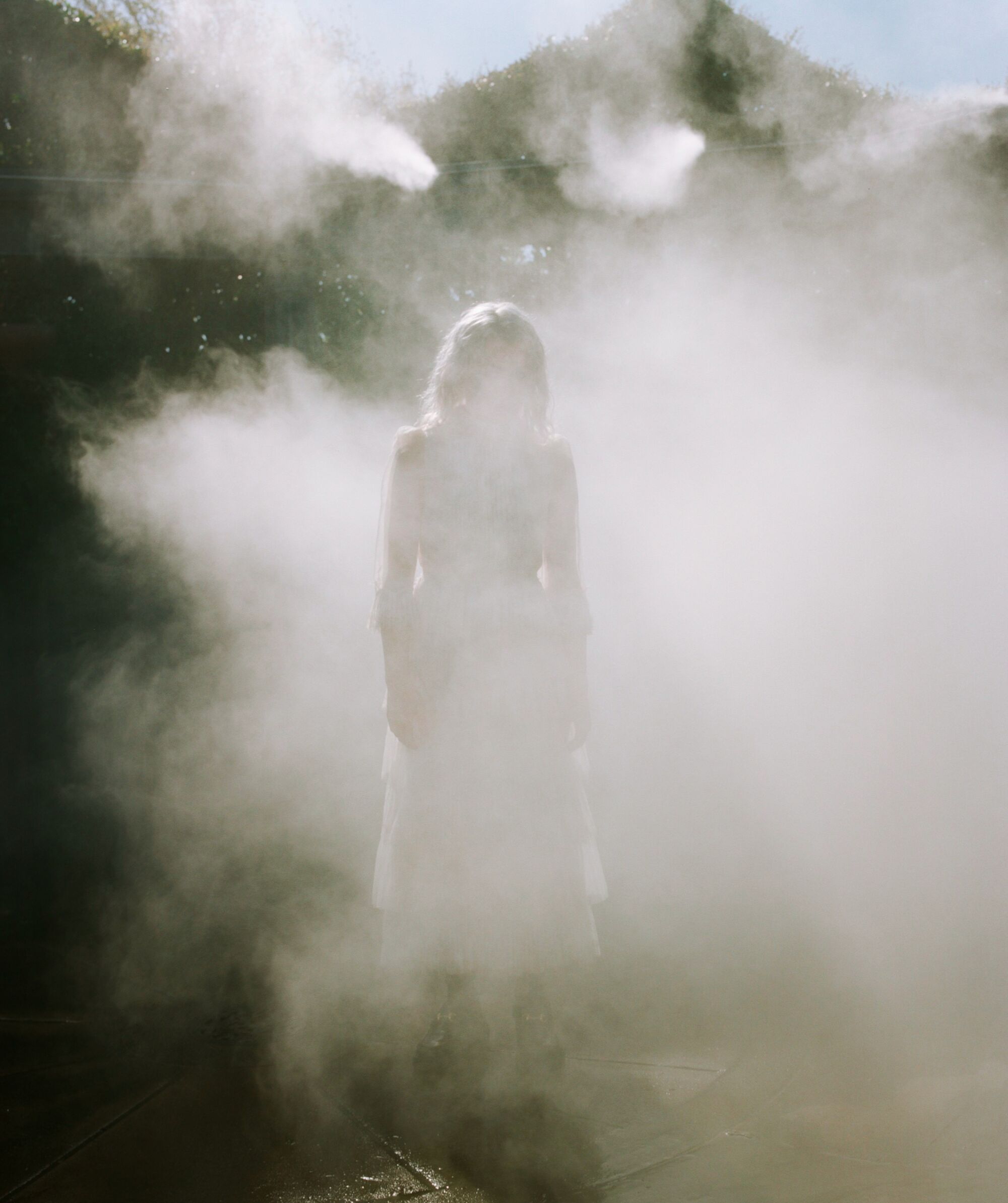 A woman stands in a cloud of mist.