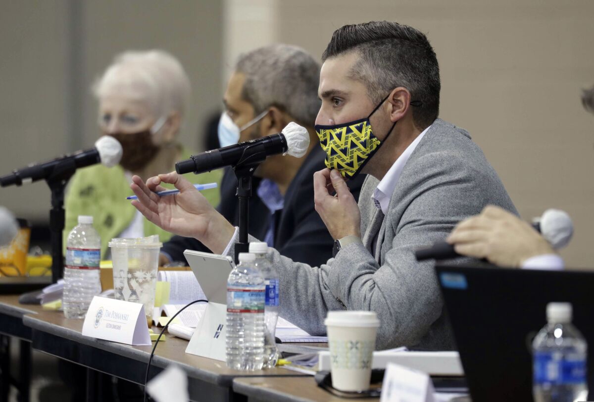 Masked Milwaukee County election officials sit at a set of tables.