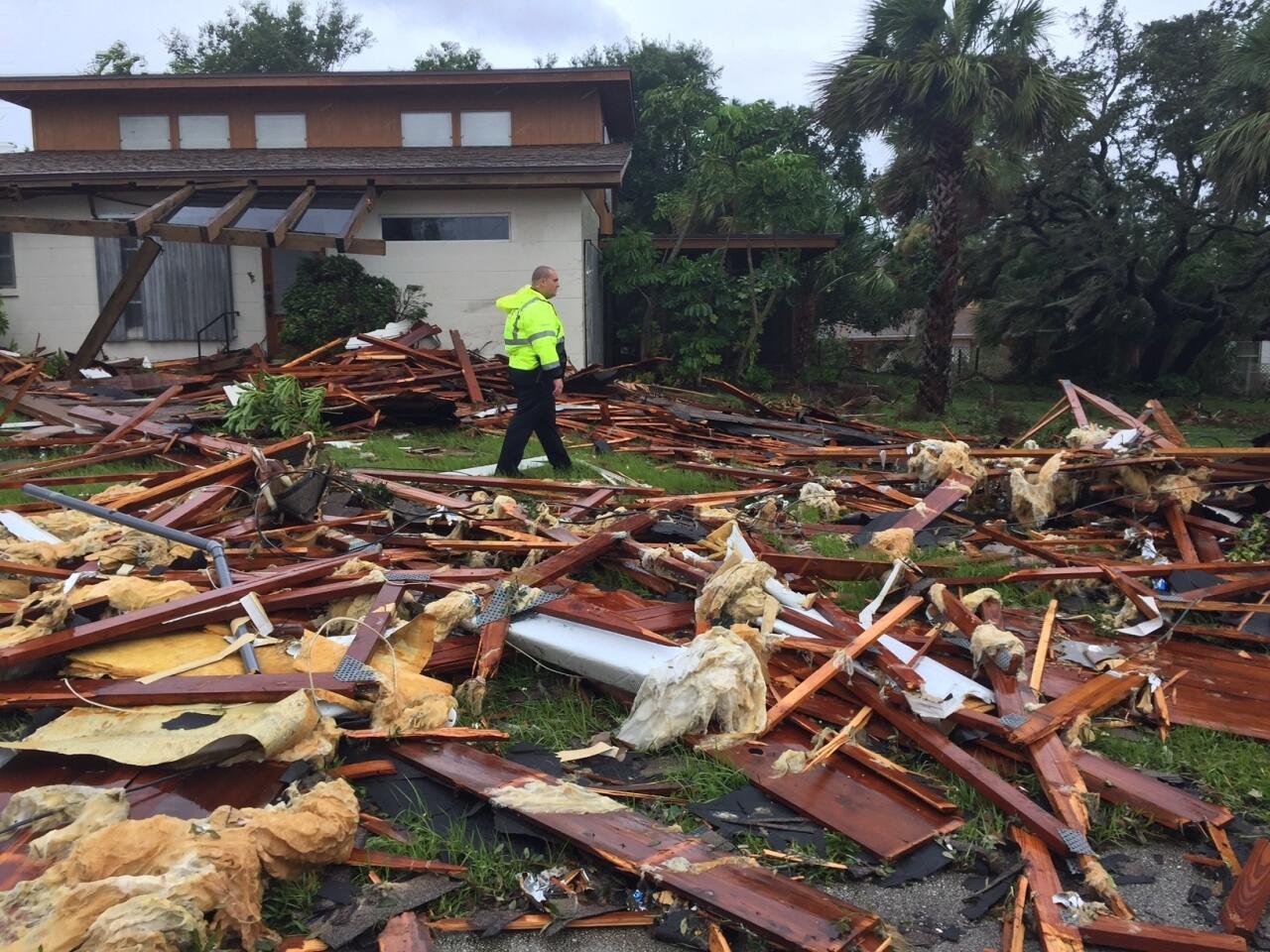 Palm Bay officer Dustin Terkoski walks over debris from a two-story home at Palm Point Subdivision in Brevard County, Fla., after a tornado touched down on Sept. 10, 2017.