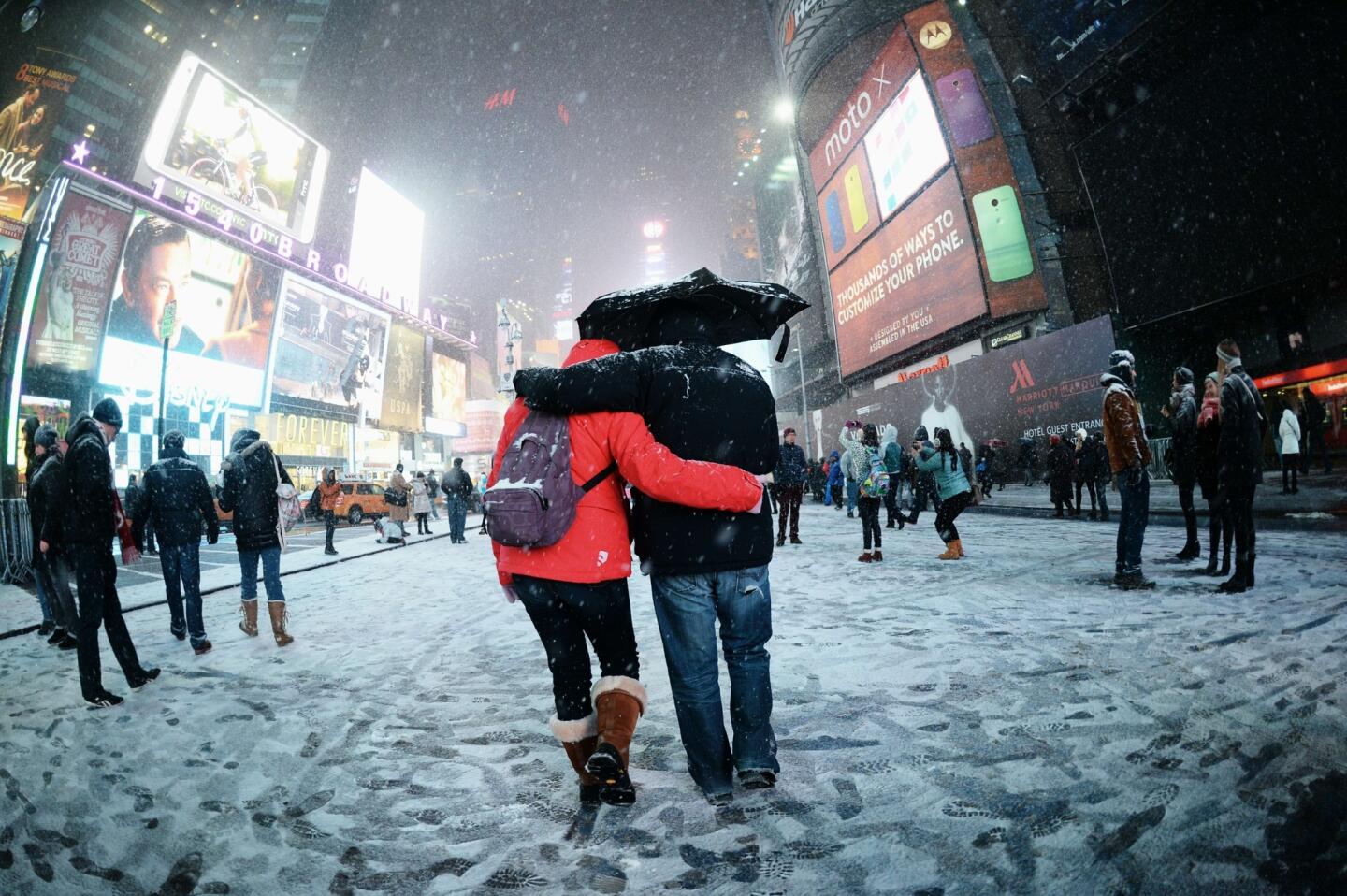 Visitors enjoy the snow on Broadway in Times Square.