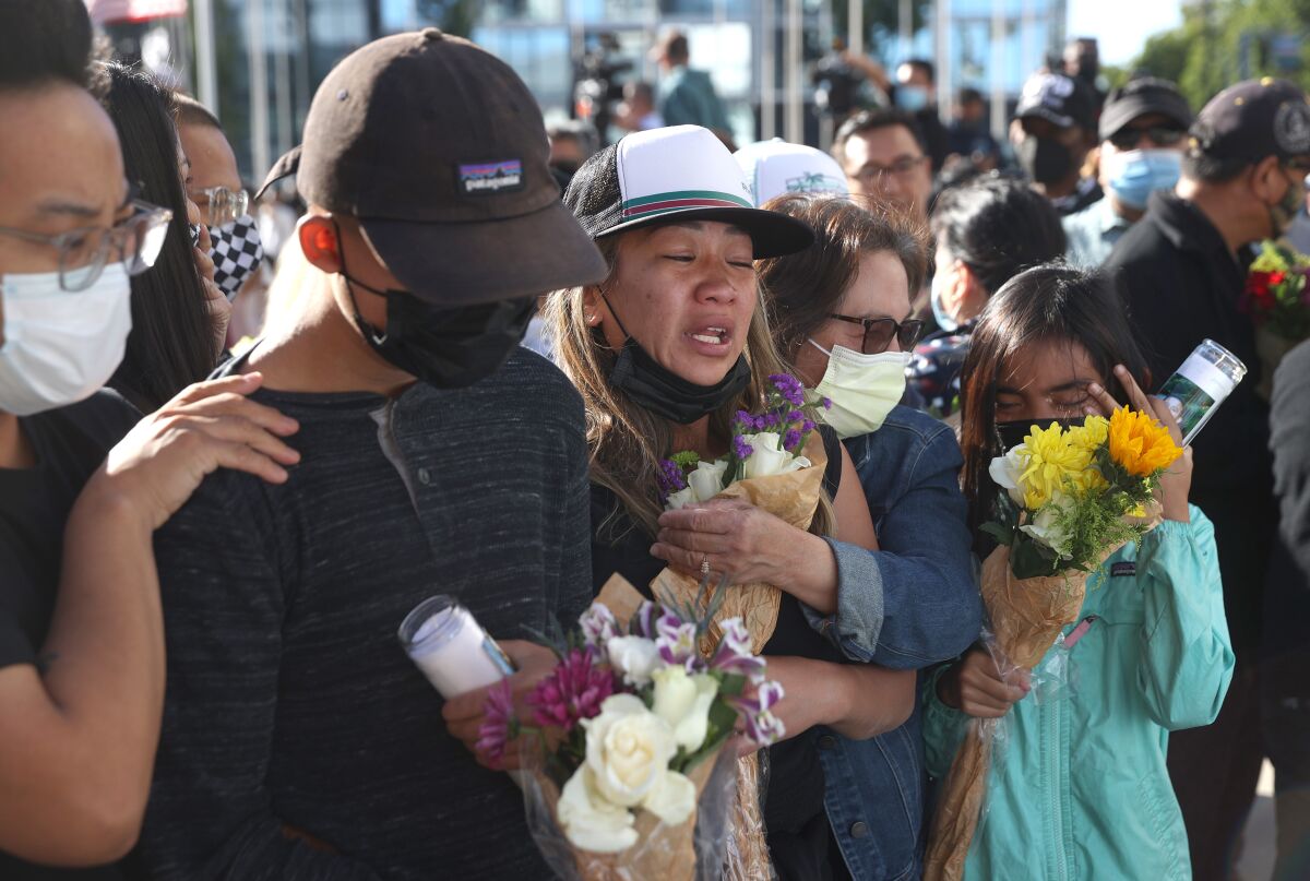 Weeping mourners hold flowers 